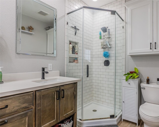 bathroom featuring walk in shower, vanity, toilet, and wood-type flooring