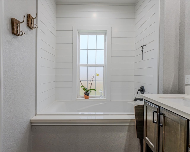 bathroom featuring plenty of natural light, a bath, and vanity