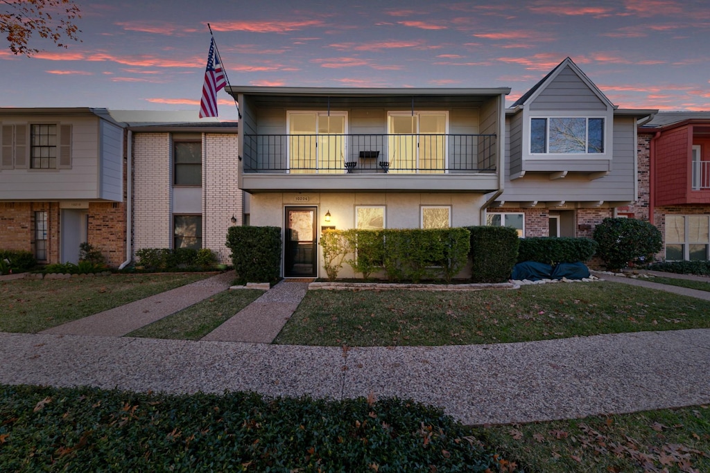 townhome / multi-family property with a balcony and a lawn