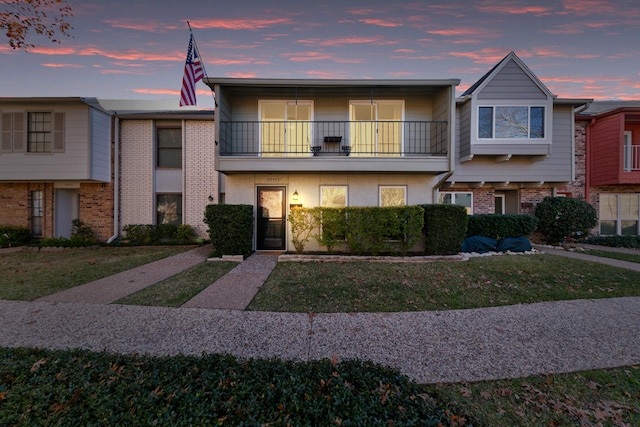 townhome / multi-family property with a balcony and a lawn