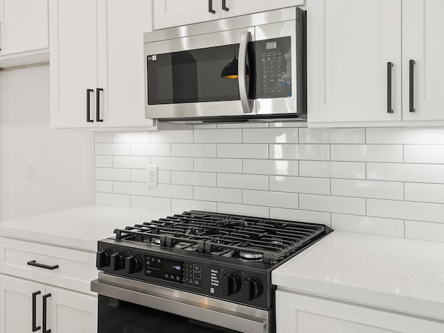 kitchen with tasteful backsplash, appliances with stainless steel finishes, light stone counters, and white cabinets