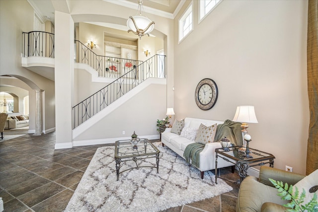 living room with a notable chandelier, ornamental molding, and a high ceiling