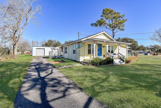 bungalow-style home with an outbuilding, a garage, a front yard, and covered porch