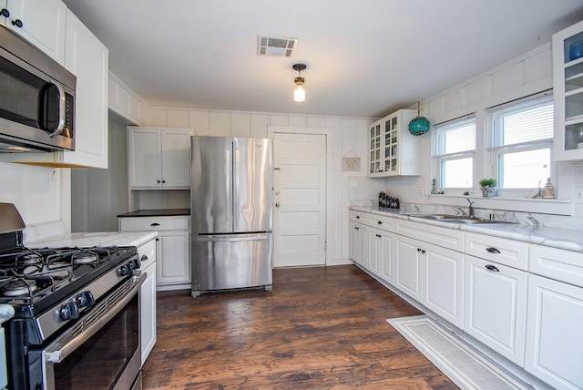 kitchen with sink, stainless steel appliances, dark hardwood / wood-style floors, light stone counters, and white cabinets