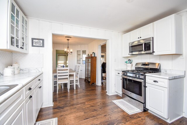 kitchen with light stone counters, appliances with stainless steel finishes, glass insert cabinets, and white cabinetry