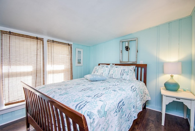 bedroom with vaulted ceiling, dark wood-type flooring, and baseboards