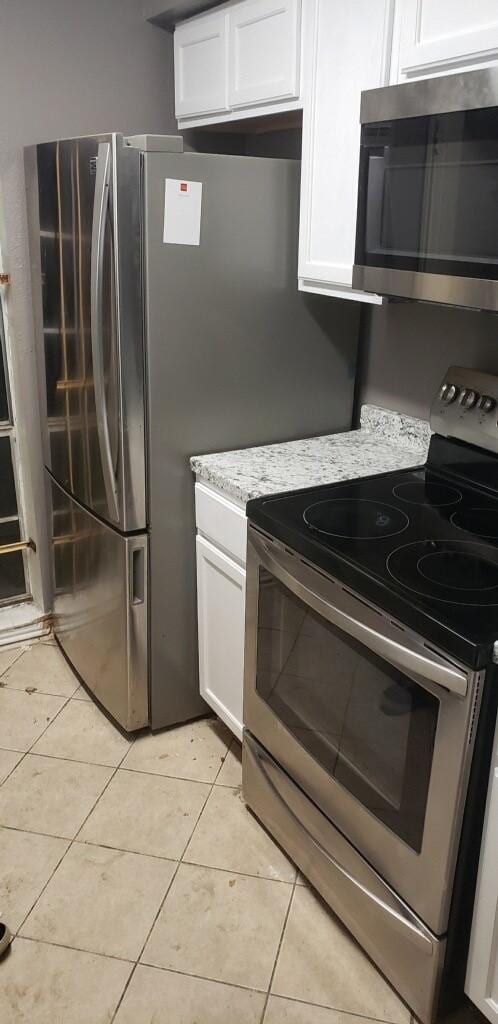 kitchen with white cabinetry, light stone countertops, light tile patterned flooring, and appliances with stainless steel finishes