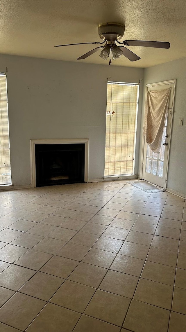 unfurnished living room with light tile patterned flooring, ceiling fan, and a textured ceiling