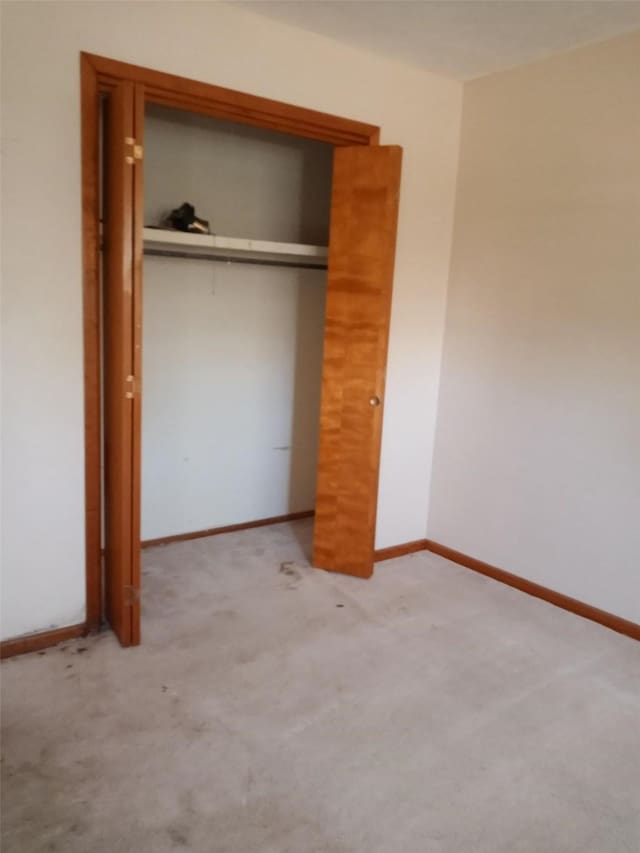 unfurnished bedroom featuring light colored carpet and a closet