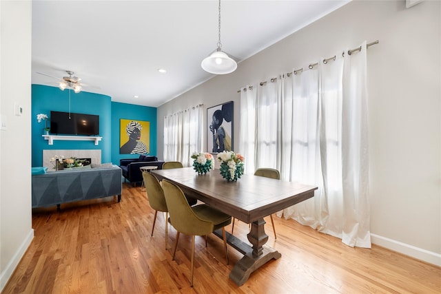 dining room with a fireplace, wood-type flooring, and ceiling fan