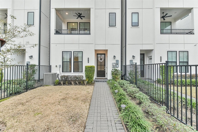 view of front of home featuring a ceiling fan, cooling unit, fence, and stucco siding