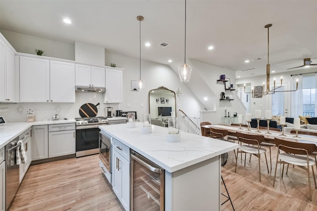 kitchen with stainless steel appliances, white cabinetry, a kitchen island, and beverage cooler