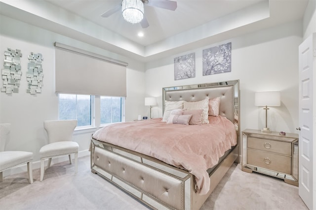 carpeted bedroom featuring a raised ceiling and ceiling fan