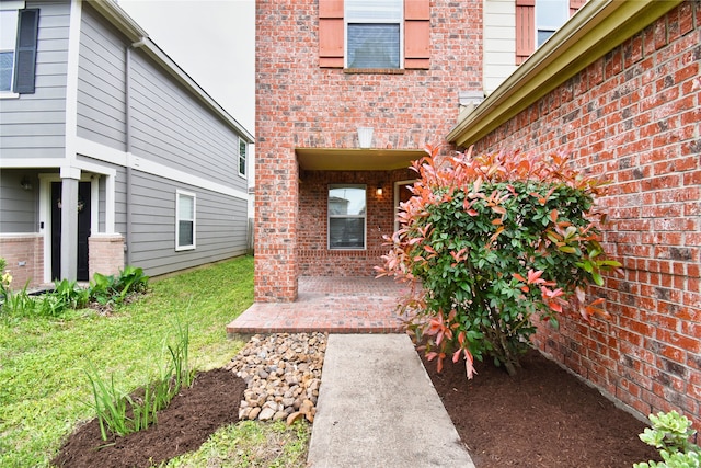 view of exterior entry with a patio and a lawn