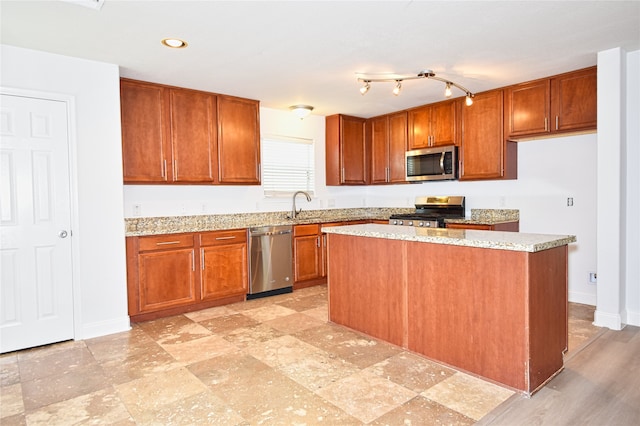 kitchen with light stone countertops, appliances with stainless steel finishes, a center island, and sink