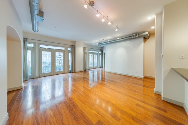 unfurnished living room with french doors and light wood-type flooring