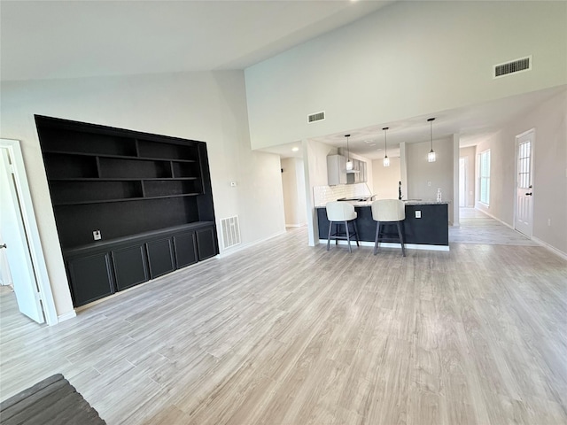 living room with light hardwood / wood-style flooring and high vaulted ceiling