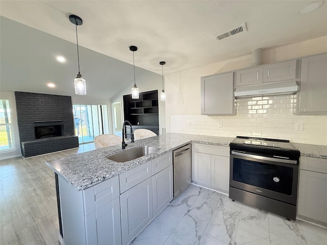 kitchen with pendant lighting, sink, appliances with stainless steel finishes, tasteful backsplash, and kitchen peninsula