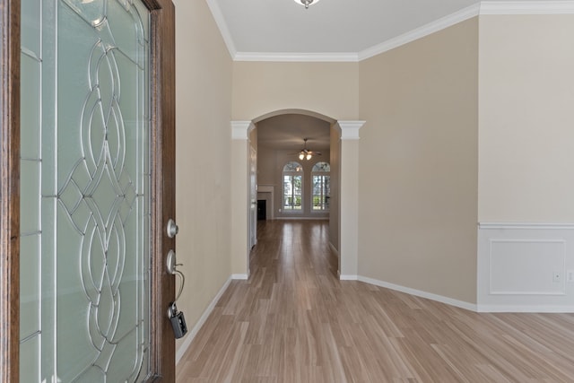 entryway with decorative columns, crown molding, ceiling fan, and light wood-type flooring