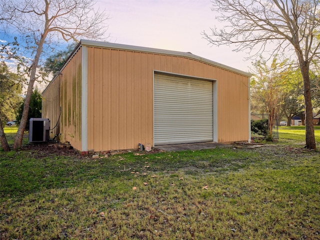 garage at dusk with cooling unit and a yard