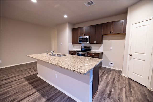 kitchen with dark wood-type flooring, stainless steel appliances, sink, and a center island with sink