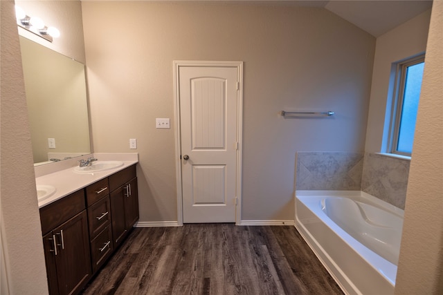 bathroom featuring a tub to relax in, vanity, vaulted ceiling, and hardwood / wood-style floors