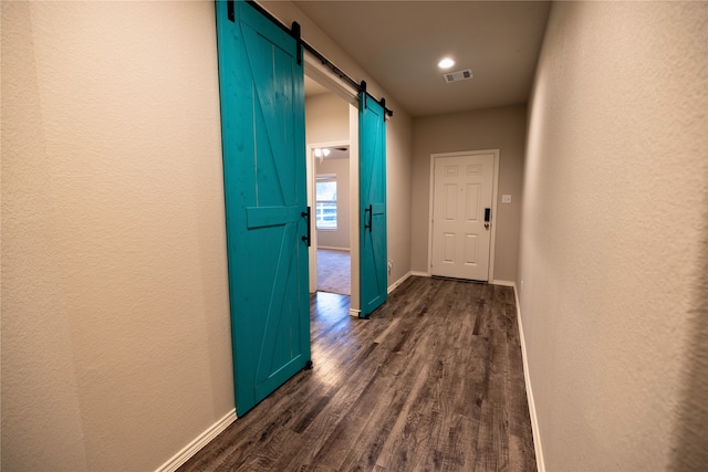 hallway featuring a barn door and dark hardwood / wood-style flooring