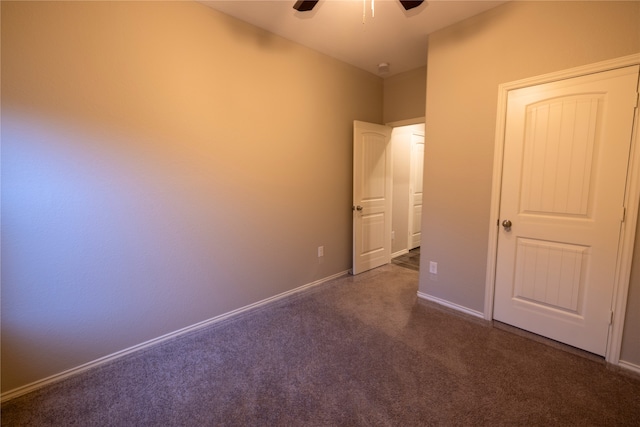 unfurnished bedroom with ceiling fan and dark colored carpet