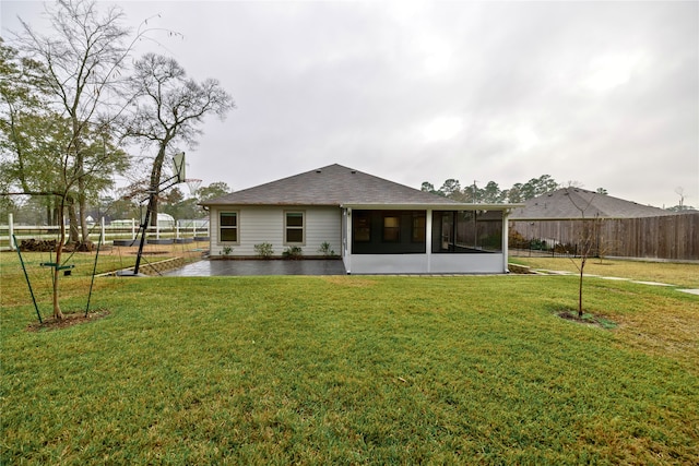 rear view of house with a yard, a patio area, and a sunroom