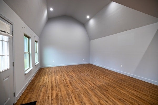 unfurnished room featuring wood-type flooring and lofted ceiling