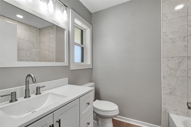 full bathroom featuring tiled shower / bath, vanity, toilet, and hardwood / wood-style floors