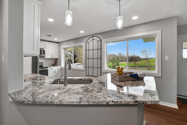 kitchen featuring hanging light fixtures, stainless steel appliances, white cabinets, and kitchen peninsula