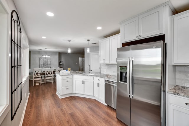 kitchen with appliances with stainless steel finishes, kitchen peninsula, and white cabinets