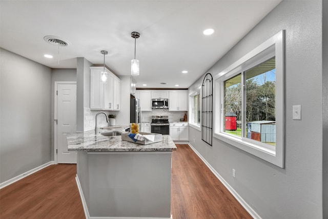 kitchen featuring pendant lighting, stainless steel appliances, sink, and white cabinets