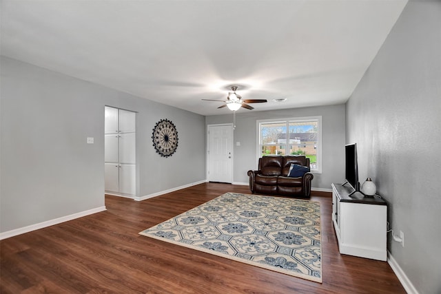 living room featuring dark wood-type flooring and ceiling fan