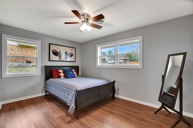 bedroom with multiple windows, ceiling fan, and dark hardwood / wood-style flooring