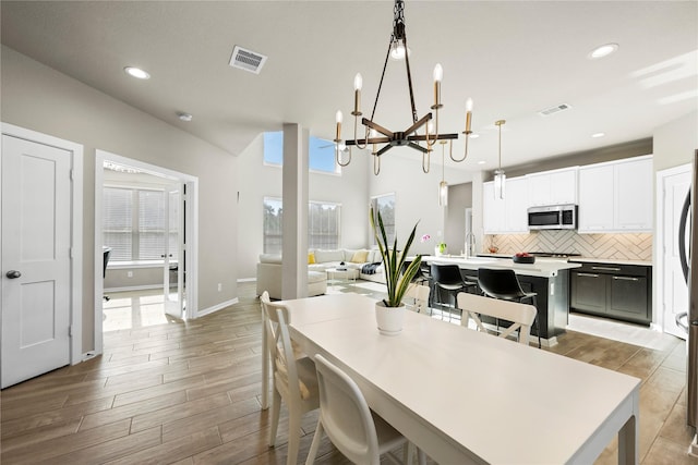 dining space with vaulted ceiling and a notable chandelier