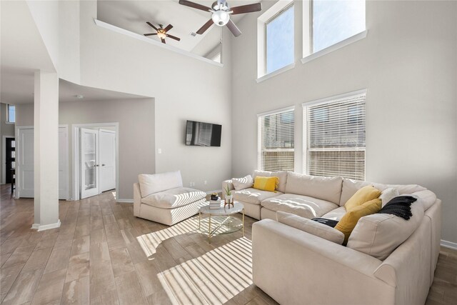 living room featuring ceiling fan, light hardwood / wood-style flooring, and a high ceiling