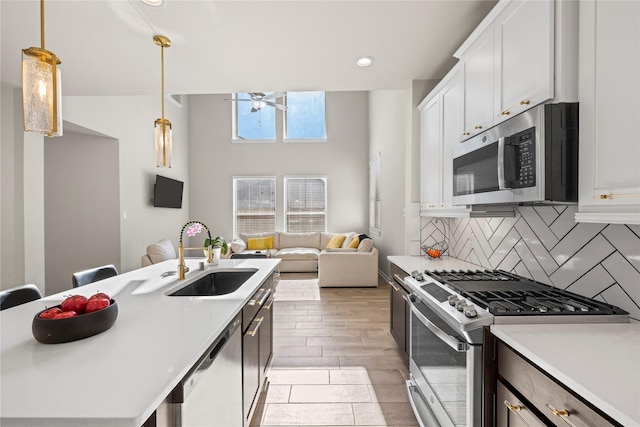 kitchen featuring sink, hanging light fixtures, white cabinets, and appliances with stainless steel finishes