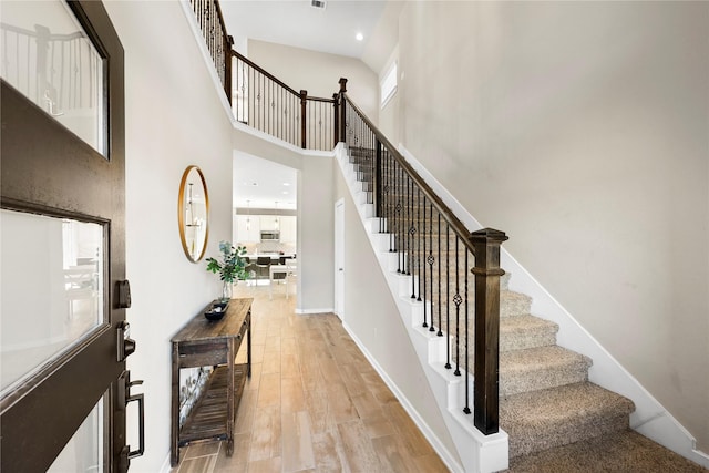 stairway featuring a high ceiling, a wealth of natural light, and hardwood / wood-style floors