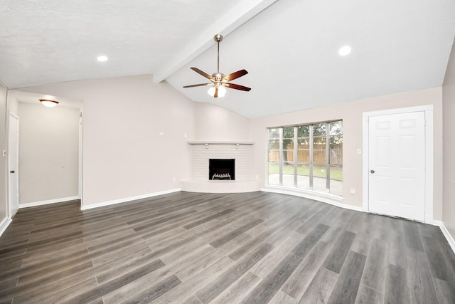 unfurnished living room featuring dark wood-type flooring, ceiling fan, a brick fireplace, and vaulted ceiling with beams