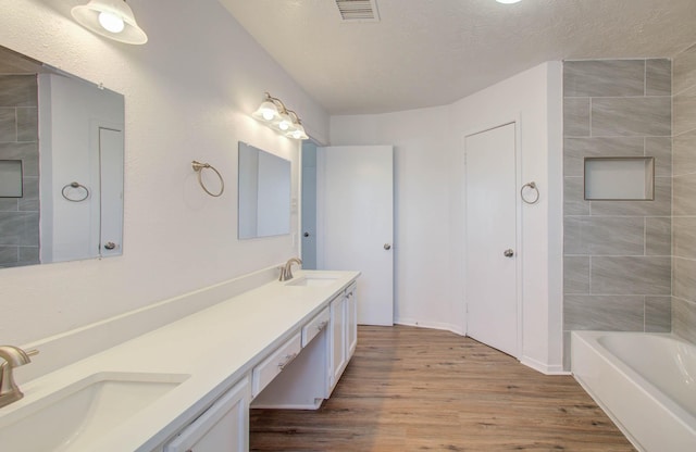 bathroom featuring hardwood / wood-style flooring, vanity, and a textured ceiling