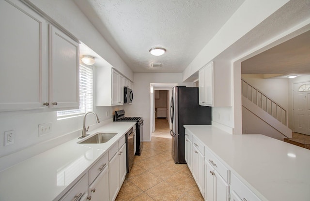 kitchen with sink, white cabinets, a textured ceiling, and black appliances