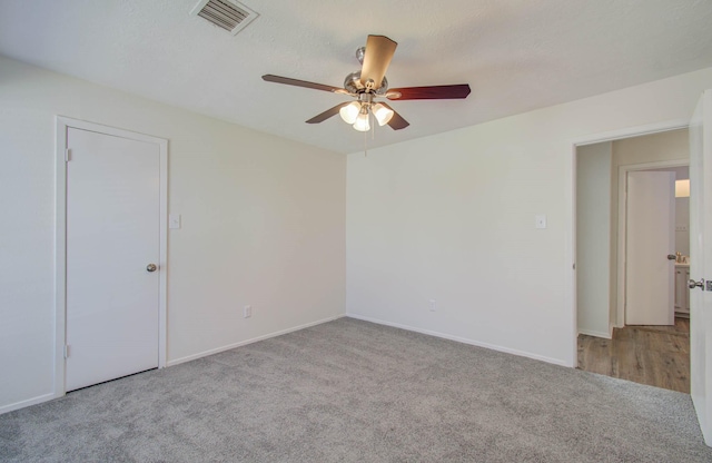 spare room with light colored carpet, a textured ceiling, and ceiling fan