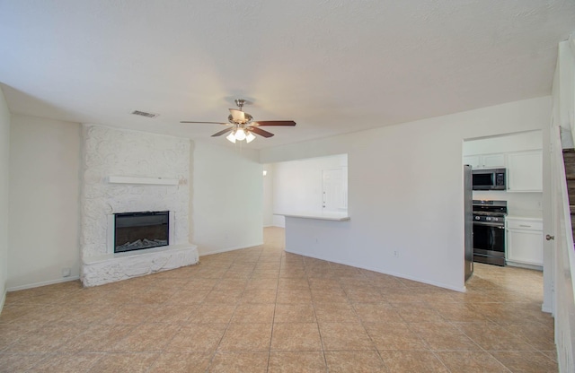 unfurnished living room with a fireplace, ceiling fan, and light tile patterned flooring