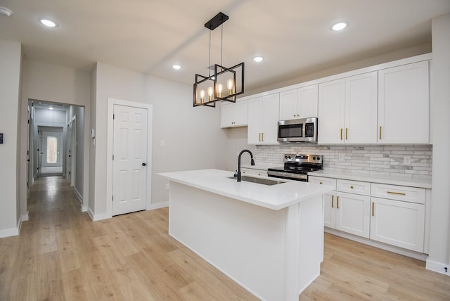 kitchen featuring pendant lighting, sink, appliances with stainless steel finishes, an island with sink, and white cabinets