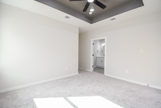 carpeted spare room with ceiling fan and a tray ceiling