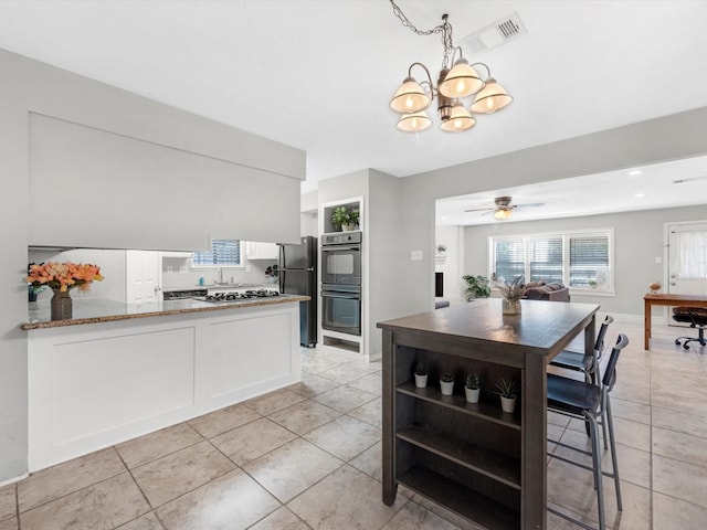 tiled dining area with ceiling fan with notable chandelier