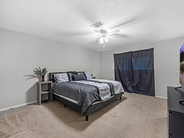 bedroom with ceiling fan, carpet, and a textured ceiling