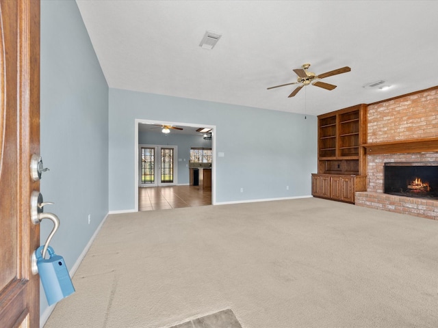 unfurnished living room with a brick fireplace, carpet, visible vents, and a ceiling fan